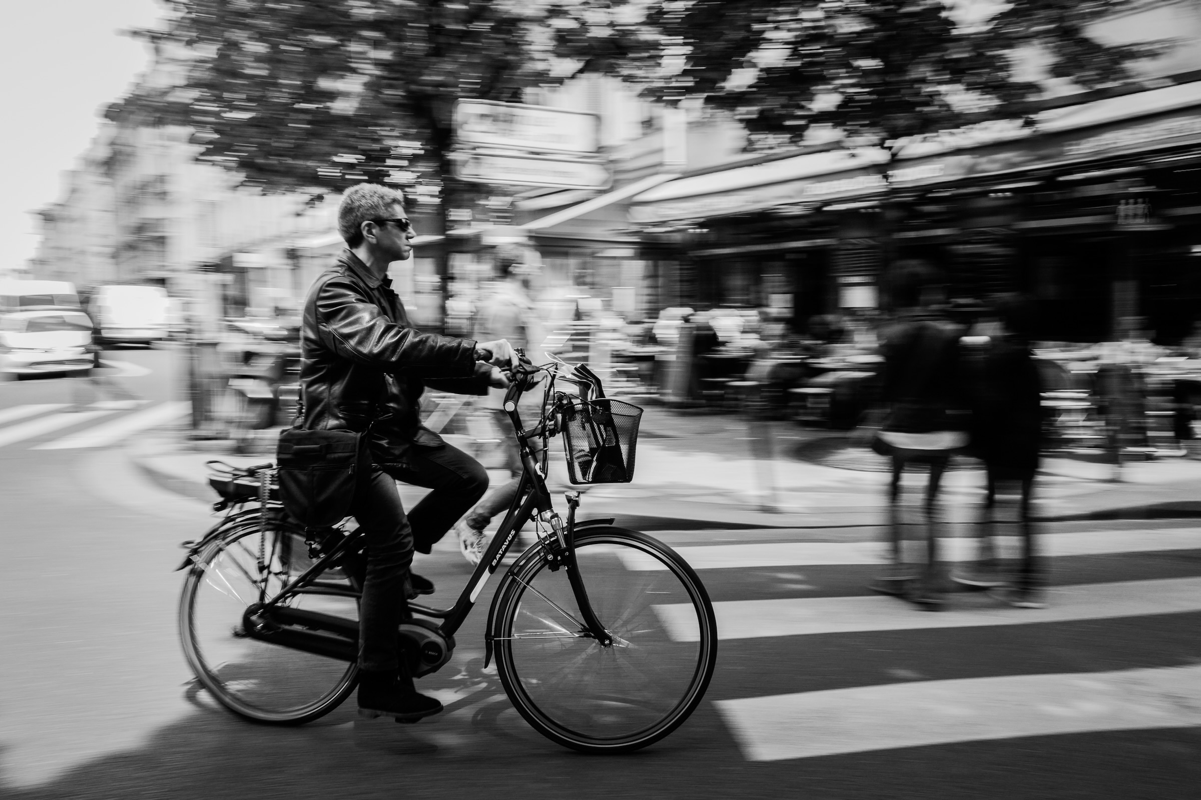 Parisian cyclist navigating historic cobblestone boulevards past Haussmann facades in Paris