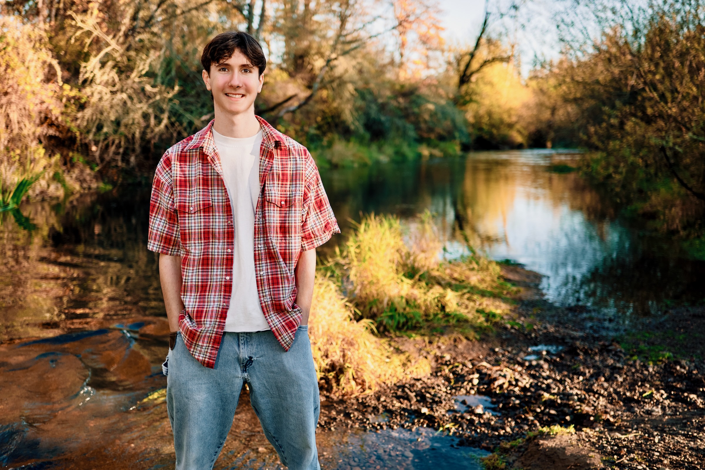 High school graduating senior photographed outdoors along a sunlit creek in Vancouver Washington